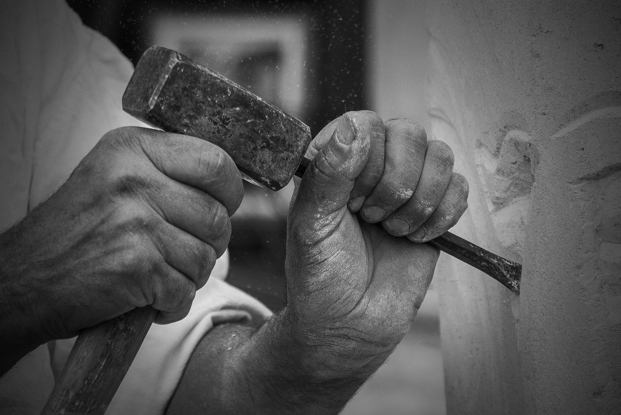 Bildhauer-Hände mit Hammer und Meißel — filigrane Handarbeit am Werkstück